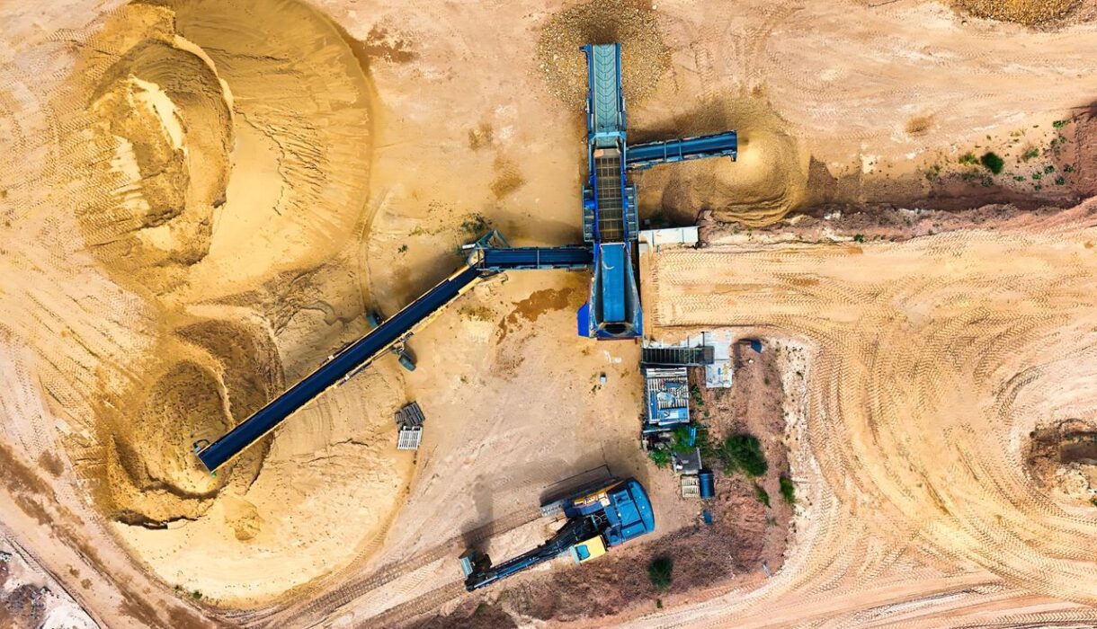 Drone shot of a sand quarry with conveyor belts and machinery in operation.