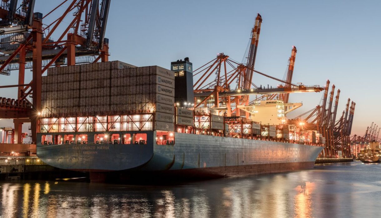 A container ship docked at Hamburg port during dusk, showcasing global trade activity.