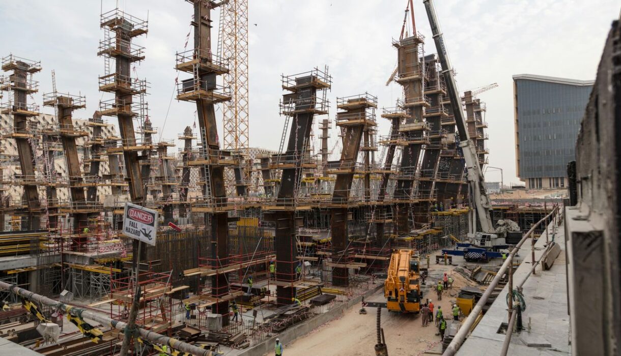 A bustling construction site with towering steel frameworks and cranes under a cloudy sky.